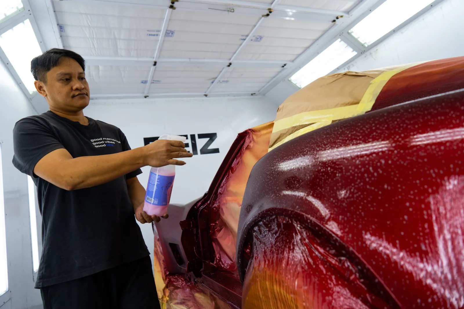 DEIZ Garage technician inspecting a freshly painted custom red body finish