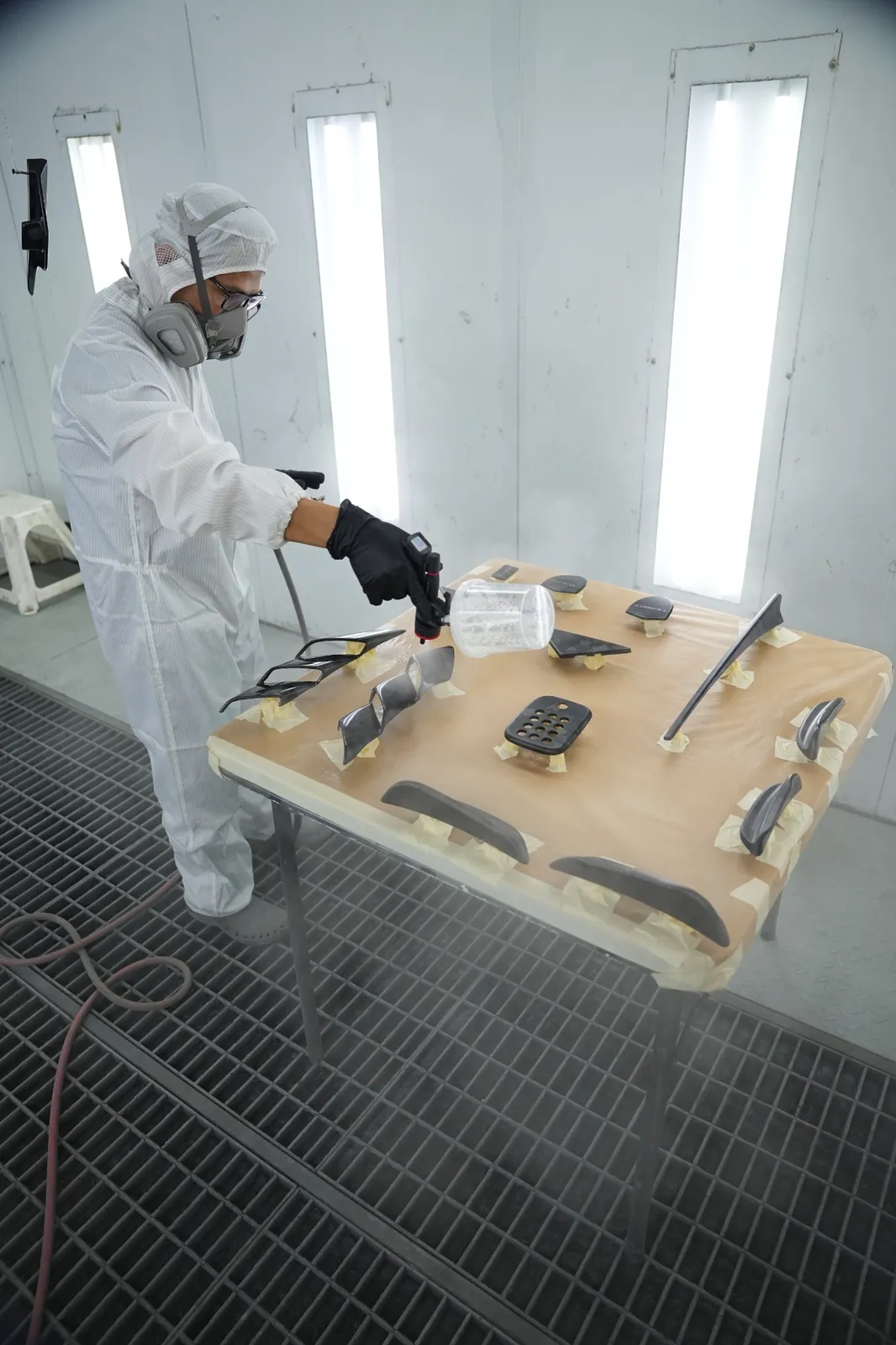 DEIZ Garage technician painting separate exterior trim components in the paint booth
