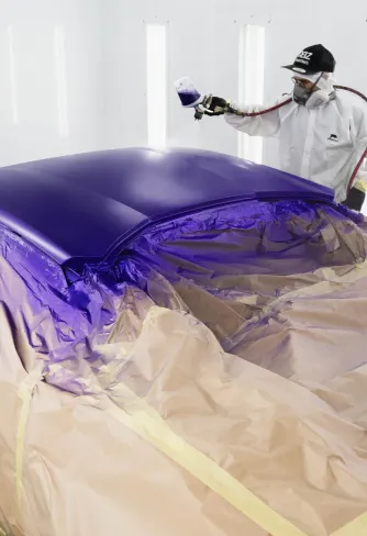 DEIZ technician spraying purple paint in the DEIZ paint booth